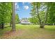 Large backyard with a lawn, mature trees, and the rear of the home at 210 Little River Farms Trl, Canton, GA 30115