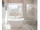 Bright bathroom featuring a soaking tub under a large window and a glass-enclosed shower with beautiful tile at 210 Little River Farms Trl, Canton, GA 30115
