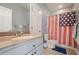 Bathroom featuring a single vanity with tan countertop, a mirror, and a shower with a decorative curtain at 210 Little River Farms Trl, Canton, GA 30115