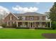 Beautiful brick home with a welcoming front porch, well-manicured lawn, and classic American flag at 210 Little River Farms Trl, Canton, GA 30115