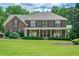 Charming brick home featuring a covered porch, manicured landscaping, and lush green lawn at 210 Little River Farms Trl, Canton, GA 30115