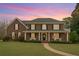 Charming brick home with a covered porch, well-manicured lawn, and inviting curb appeal at dusk at 210 Little River Farms Trl, Canton, GA 30115