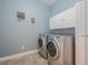Well-organized laundry room featuring a side-by-side washer and dryer, white cabinets, and light blue walls at 210 Little River Farms Trl, Canton, GA 30115