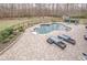 A kidney-shaped in-ground pool with tanning ledge sits on a stone paver patio with lounge furniture at 210 Little River Farms Trl, Canton, GA 30115