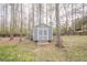 View of the backyard storage shed with double doors and simple design, set amidst trees and landscaping at 210 Little River Farms Trl, Canton, GA 30115