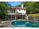 Back of home featuring a kidney-shaped pool with a stone retaining wall and stairs leading up to a back deck at 1260 Heards Ferry Rd, Sandy Springs, GA 30328