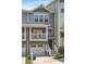 Gray townhouse featuring a covered porch with white columns, a garage, and well-maintained landscaping at 2015 Liberty Nw Ct, Atlanta, GA 30318