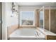 Bathroom featuring a soaking tub, glass enclosed shower, and a large window at 501 White Oak Path, Canton, GA 30115