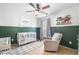 Bedroom with board and batten accent wall, crib, and light gray chair at 501 White Oak Path, Canton, GA 30115