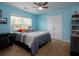 Light blue bedroom with a ceiling fan, plush carpet, and a large window that lets in plenty of natural light at 5976 Rosie Se Ln, Mableton, GA 30126