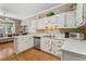 Well-lit kitchen featuring white cabinetry, stainless steel dishwasher, and hardwood floors at 1201 Bridle Path, Marietta, GA 30068