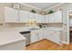 Well-lit kitchen featuring a stainless steel dishwasher, plenty of cabinet space, and a view to the dining room at 1201 Bridle Path, Marietta, GA 30068