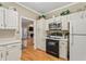 Modern kitchen with stainless steel microwave, oven, refrigerator and a view to the adjacent living room at 1201 Bridle Path, Marietta, GA 30068