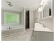 Bright bathroom showcasing a soaking tub beneath a window and double sink vanity with marble floors at 1502 Lake Koinonia Dr, Woodstock, GA 30189