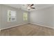 Cozy bedroom featuring neutral walls, plush carpet, two windows, and a ceiling fan at 1502 Lake Koinonia Dr, Woodstock, GA 30189