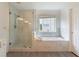 Bright bathroom featuring marble, a large soaking tub, a seamless glass shower, and modern fixtures at 5281 Tormeall Trce, Suwanee, GA 30024