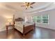 Large primary bedroom featuring a four-poster bed, hardwood floors, tray ceilings, and plenty of natural light at 5281 Tormeall Trce, Suwanee, GA 30024