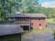 Aerial shot reveals the house's brick exterior, porch, and surrounding lush greenery, offering a private retreat at 664 Mcburnette Ne Rd, Marietta, GA 30068