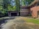 Backyard view showcasing a two-story brick house, screened-in porch, shed, and driveway surrounded by trees at 664 Mcburnette Ne Rd, Marietta, GA 30068