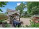 An outdoor patio featuring a gazebo with an outdoor kitchen and a fire pit, surrounded by lush landscaping at 115 Ocee View Ct, Alpharetta, GA 30022