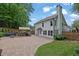 A beautiful backyard with a large stone patio, outdoor kitchen, lush landscaping, and a lovely white home at 115 Ocee View Ct, Alpharetta, GA 30022