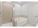 Well-lit bathroom featuring a tub with shower and neutral tilework at 401 Village Ln, Fairburn, GA 30213