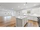 Open kitchen with white island, stainless appliances, and wood floors next to living area at 401 Village Ln, Fairburn, GA 30213