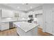 Well-lit kitchen boasts stainless steel appliances, white cabinets, a bright island, and hardwood floors at 401 Village Ln, Fairburn, GA 30213
