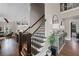 Elegant staircase with dark wood railing and a view of the kitchen and living area at 5025 Savannah Run, Cumming, GA 30040