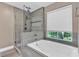 This bathroom features a soaking tub with a glass shower and natural light from the window at 2766 Stonecreek Se Rd, Smyrna, GA 30080
