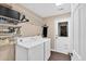 Bright laundry room features a white washer and dryer, wire shelving, and wood flooring at 2766 Stonecreek Se Rd, Smyrna, GA 30080