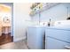 Well-lit laundry room with modern machines, open shelves, and tile floor, and access to powder room at 468 Scott Farm Dr, Powder Springs, GA 30127
