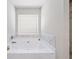 Relaxing bathtub with elegant marble surround and natural light from the window above at 20 Tarpley Way, Covington, GA 30016