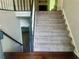 Carpeted staircase with dark wood and white banisters connect the home's levels, next to gray walls and wood floors at 4790 Brandon Acres Ln, Buford, GA 30519