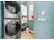 Convenient laundry room featuring stacked washer and dryer with blue walls and shelving at 1265 Timberline Pl, Alpharetta, GA 30005