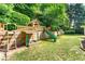 Outdoor playset with slide, sand pit, and climbing area in a well-maintained yard surrounded by nature at 1265 Timberline Pl, Alpharetta, GA 30005