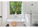 Bright bathroom featuring modern tub, shower, and large window view to nature at 2585 Hickory Rd, Canton, GA 30115
