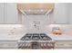 Close-up of a modern stainless steel gas range with a wooden range hood and marble countertops at 2585 Hickory Rd, Canton, GA 30115