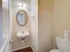 Cozy powder room with a pedestal sink, decorative mirror, and neutral color scheme at 1761 Stoney Chase Dr, Lawrenceville, GA 30044
