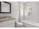 Well-lit bathroom with granite vanity, framed mirror, and tub-shower featuring elegant white tiling and recessed shelving at 763 Jones Nw Ave, Atlanta, GA 30314