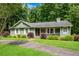 Charming ranch home featuring a covered front porch, green siding, white shutters, and lush landscaping at 789 Concord Sw Rd, Smyrna, GA 30082