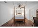Primary bedroom with hardwood floors, a four-poster bed, and white walls at 385 Guildhall Grv, Johns Creek, GA 30022