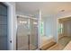 A bright bathroom features a glass shower, soaking tub, and natural light from the window at 9050 Brockham Way, Alpharetta, GA 30022