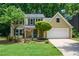 Charming home features a manicured lawn, mature trees, and a two-car garage at 9050 Brockham Way, Alpharetta, GA 30022