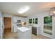 Bright kitchen features white cabinetry, stainless steel sink, and center island, and backyard views at 9050 Brockham Way, Alpharetta, GA 30022