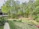 View of the home's backyard with lush landscaping, mature trees, and a fire pit, creating a serene outdoor oasis at 710 Bentgrass Ct, Dacula, GA 30019
