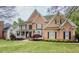 A beautiful two-story brick home with a lush green lawn and mature trees in a suburban setting at 710 Bentgrass Ct, Dacula, GA 30019