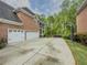 Spacious three-car garage alongside a brick home, enhanced by a basketball hoop and mature trees at 710 Bentgrass Ct, Dacula, GA 30019