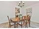 Dining room featuring a wooden table, chandelier, neutral walls, light-colored flooring, and a glimpse into the kitchen at 108 Shawville Ln, Peachtree City, GA 30269