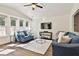 Bright living room with hardwood floors, ceiling fan, blue sofas, multiple windows, and a cozy atmosphere at 108 Shawville Ln, Peachtree City, GA 30269